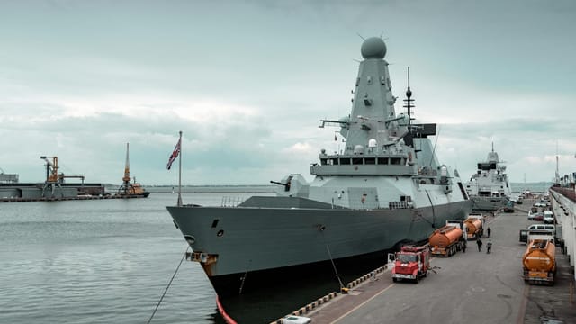 A navy destroyer docked at Odesa harbor with cloudy sky, highlighting maritime defense.
