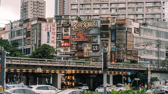 Bustling city street with diverse building signs and traffic below.