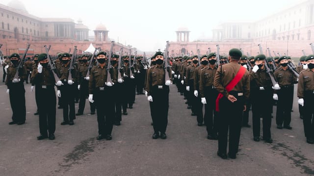 Soldiers in formation during a foggy military parade with uniforms and rifles.