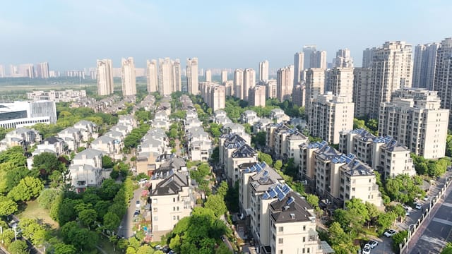 Aerial view of modern residential area with high-rise apartments and greenery on a sunny day.