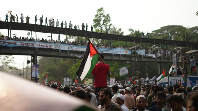 Large crowd in Dhaka rallying with Palestinian flags during a pro-Palestine protest.