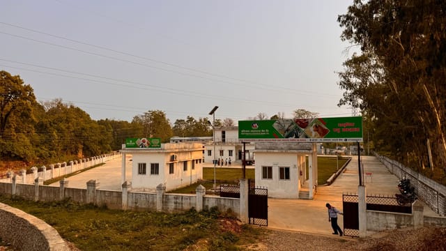 A rural facility with an open gate, surrounded by trees and a sunset sky, presents a peaceful rural setting.