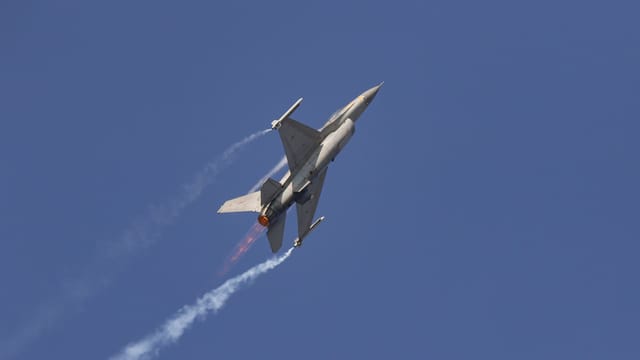 A jet fighter soars impressively through a clear blue sky, showcasing power and agility.