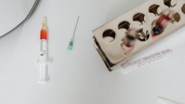 Syringe and needle with blood samples in a laboratory setting, capturing healthcare diagnostics.