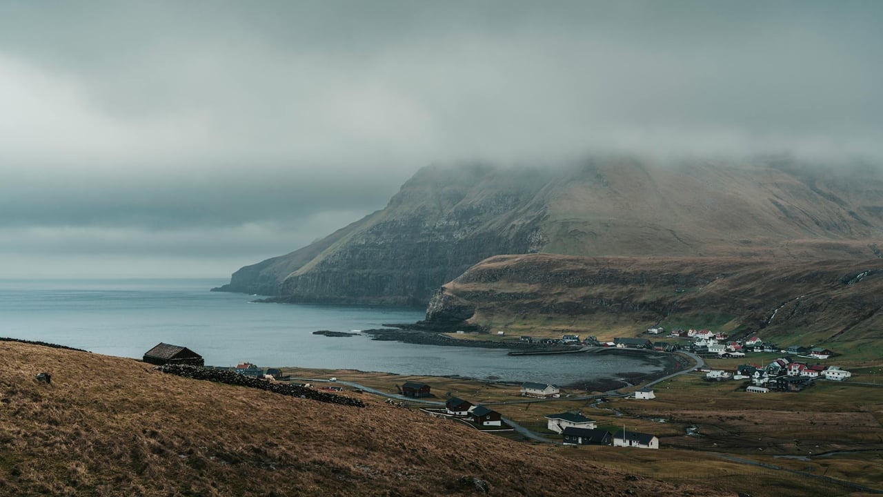 Serene view of a foggy coastline and village in the Faroe Islands.