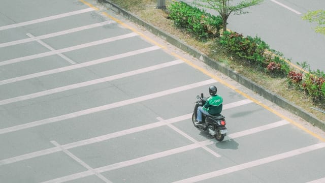 A Grab motorbike rider on a quiet street captured from above, symbolizing urban mobility.