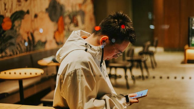 A young man focused on his smartphone in a trendy Nanjing café.