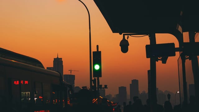 Silhouette of Chongqing tram station with urban skyline and sunset backdrop.