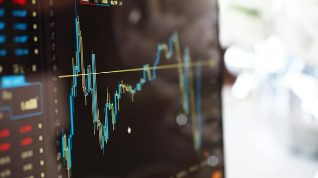 Detailed view of financial trading graphs on a monitor, illustrating stock market trends.