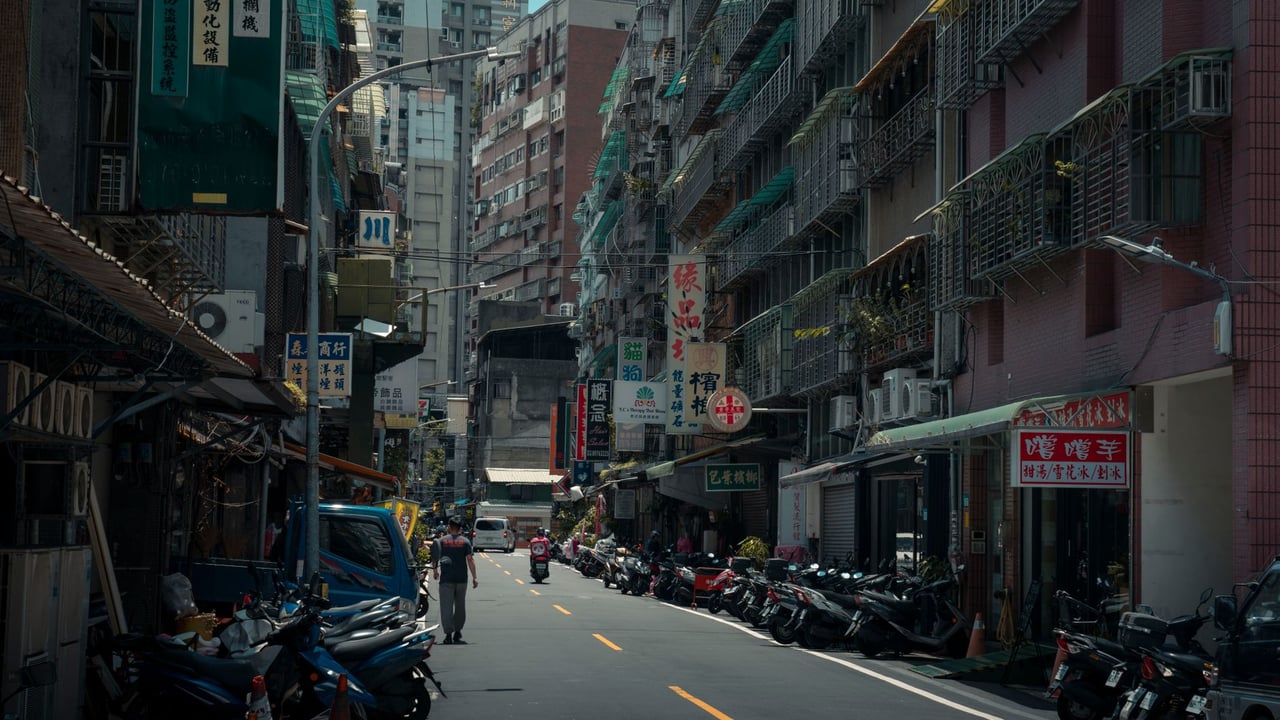 A bustling urban street with lined motorcycles and towering old buildings.