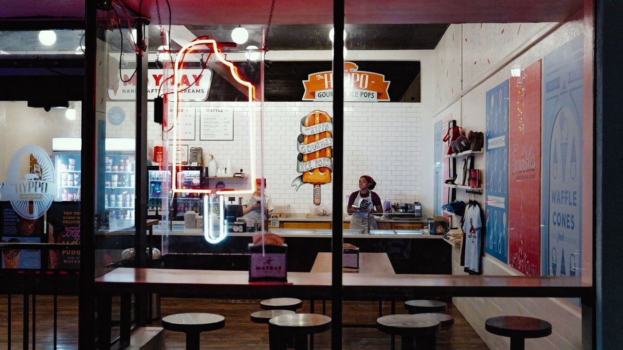 Vibrant ice cream shop with neon signs viewed from outside at night.