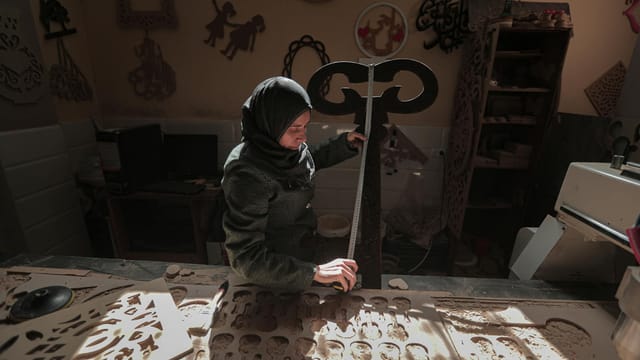 A female artisan working on wood in a Gaza workshop, showcasing craftsmanship and tradition.