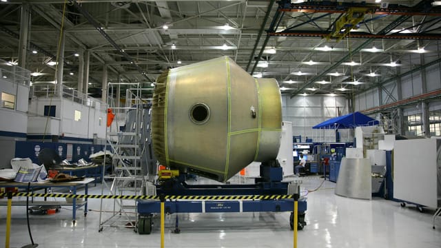 Heavy detail of spacecraft placed on rolling platform under construction at futuristic rocket factory