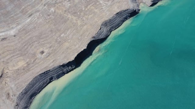 Aerial image showcasing a rocky coastline and turquoise water in Papan, Kyrgyzstan.