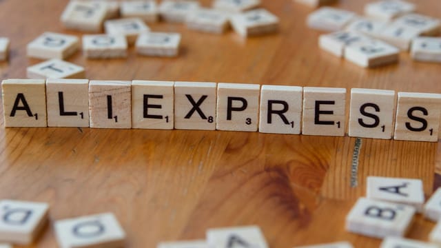Close-up of Scrabble tiles forming AliExpress on a wooden surface, ideal for ecommerce and retail themes.