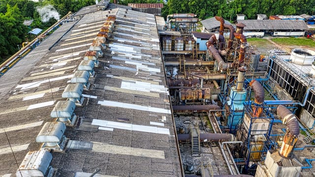 Illustrative image: From above of industrial area of factory with large equipment placed in city among green trees in daylight