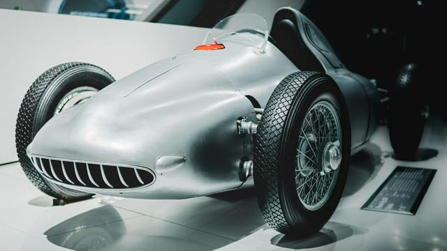 Vintage race car on display in a modern museum setting. Ideal for historical automotive concepts.