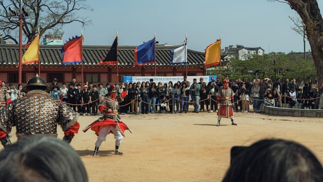 A dynamic martial arts demonstration with traditional Korean attire in Seoul, attracting a diverse audience.