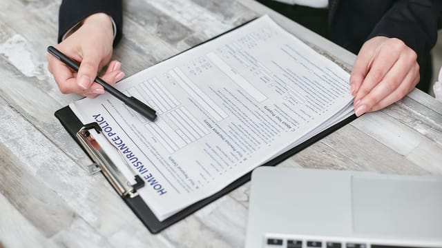 Close-up of hands reviewing a home insurance policy, emphasizing professionalism and finance.