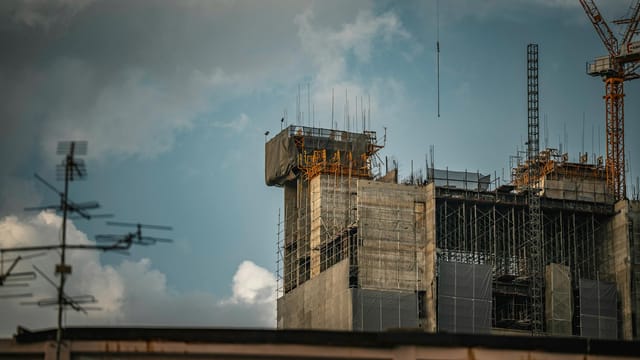 Construction scene of a high-rise building in Bangkok, Thailand with dramatic cloudy sky.