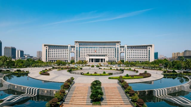 Stunning architectural building with symmetrical design and a reflecting pool, set against a clear blue sky.