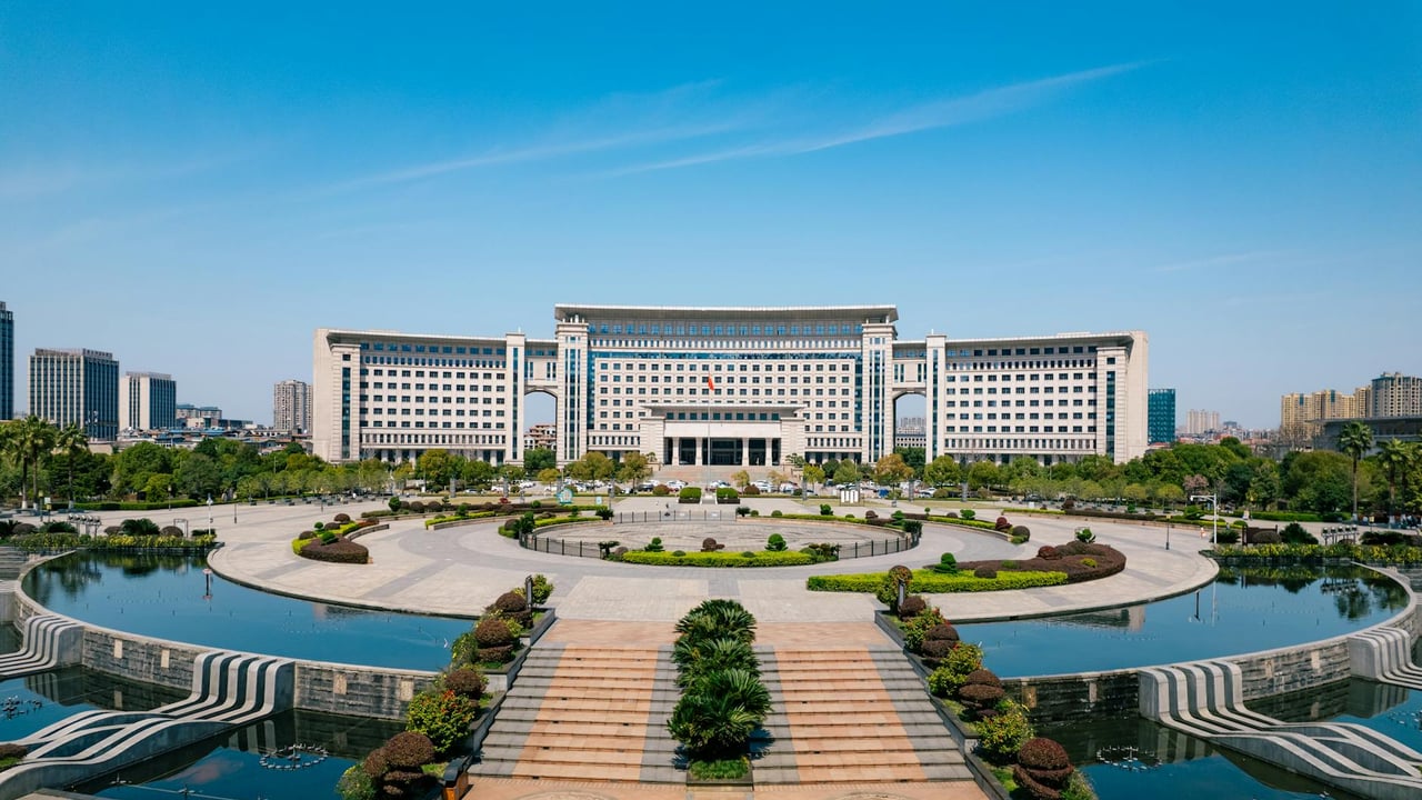Stunning architectural building with symmetrical design and a reflecting pool, set against a clear blue sky.