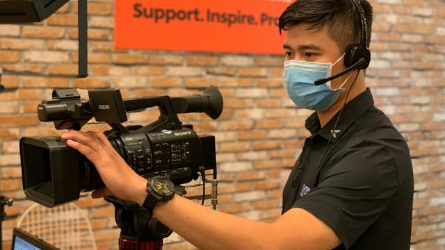 Professional videographer with headset operating camera in an indoor studio setting.