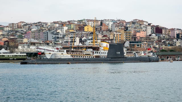 Panoramic view of Istanbul harbor showcasing a historical submarine against colorful cityscape.