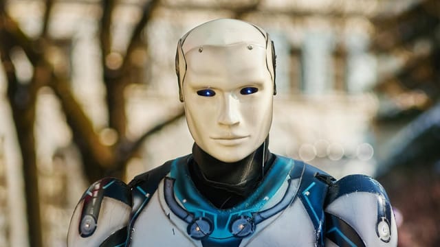 Close-up of a humanoid robot with a futuristic design posing outdoors.