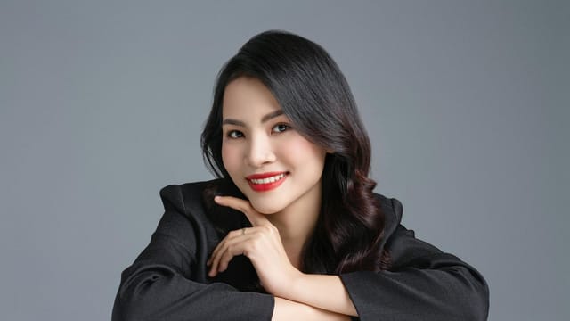Professional studio portrait of a smiling woman in a black blazer, exuding confidence and elegance.