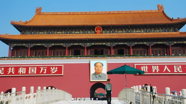 Iconic Tiananmen Gate in Beijing featuring Mao Zedong portrait under clear blue skies.