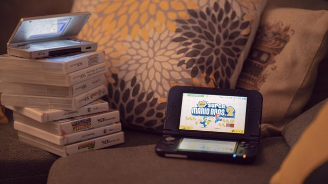 Two handheld gaming consoles on a sofa with game cartridges, creating a cozy game night mood.