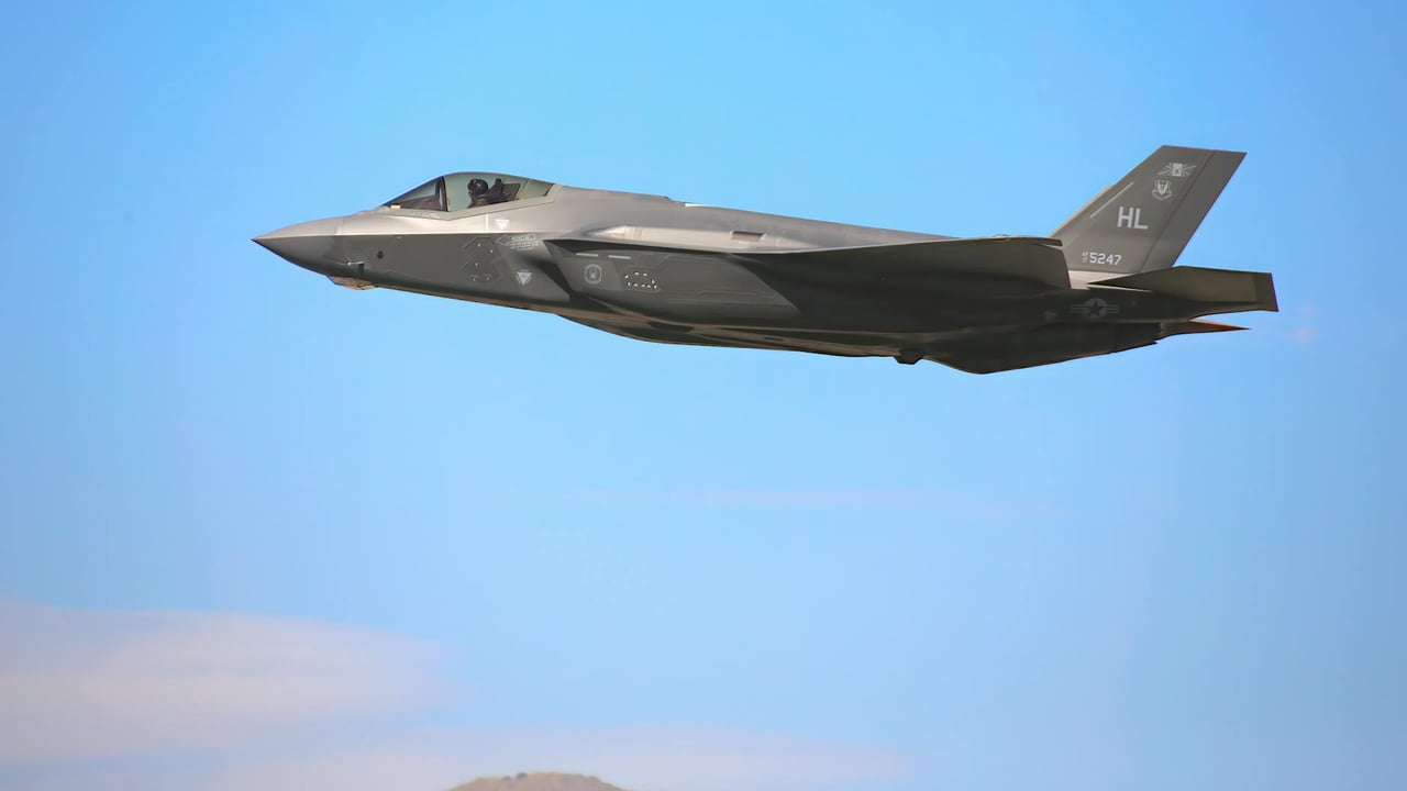 A sleek F-35A military jet flying against a clear blue sky in Nevada.