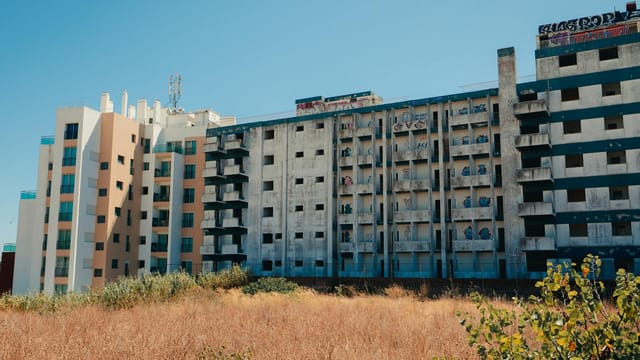 Deserted apartment buildings in Faro, Portugal under a clear blue sky.