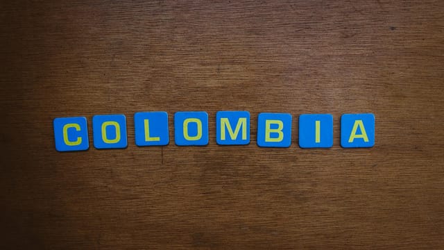 A close-up of colorful tile letters spelling 'Colombia' on a wooden surface.