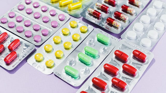 Close-up of various colorful pills in blister packs, showcasing diverse medicine types.