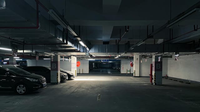 A dark underground parking garage with parked cars and minimal lighting in Wuxi, Jiangsu.