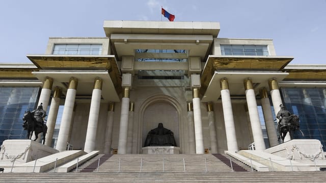 Front view of the historic Government Palace in Ulaanbaatar with Genghis Khan statue and columns.