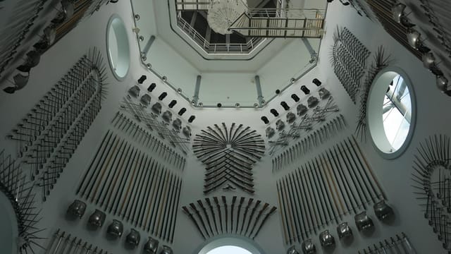 A collection of medieval weapons on display in a historic armory room with ornate design.