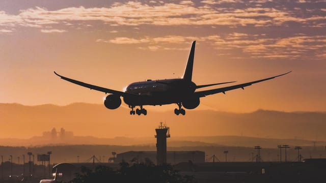 Silhouette of an airplane landing at sunset in Tel Aviv, with a beautiful golden sky.