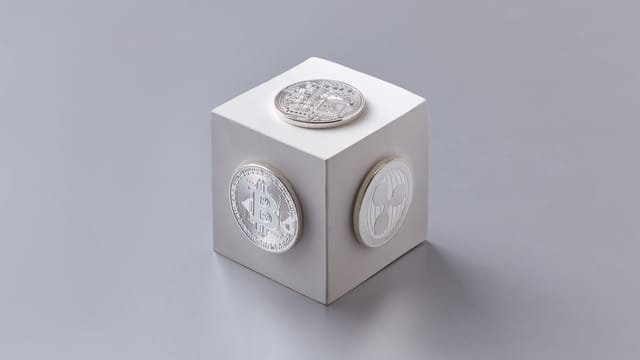 A modern composition of silver cryptocurrency coins on a white cube, ideal for finance concepts.