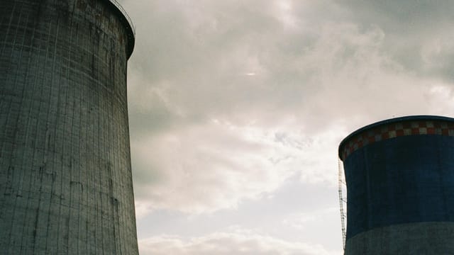 Imposing cooling towers of a nuclear power station under a cloudy sky, showcasing industrial architecture.