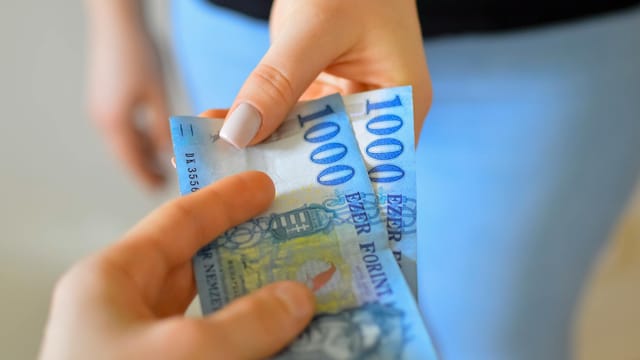 An exchange of 1000 Hungarian Forint banknotes between two hands.