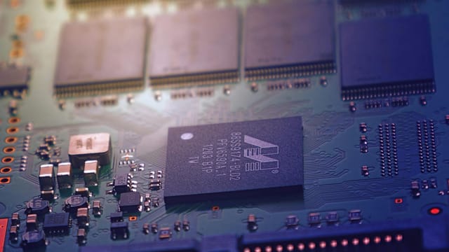 Detailed image of an electronic circuit board showing microchips and intricate wiring in a modern technological setting.