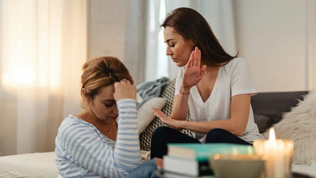 Two women in a tense emotional exchange in a cozy home setting.