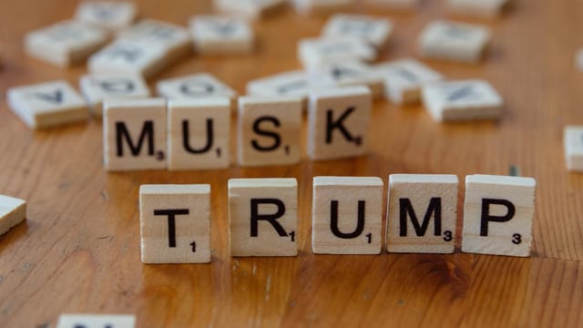 Scrabble game tiles notably spell out 'Musk' and 'Trump' on a wooden table, sparking cultural conversation.