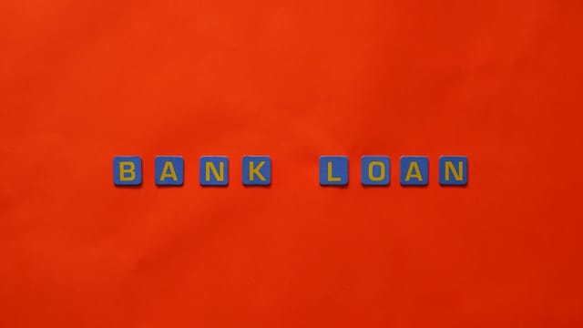 Letters forming 'Bank Loan' on a vibrant red surface, ideal for finance themes.
