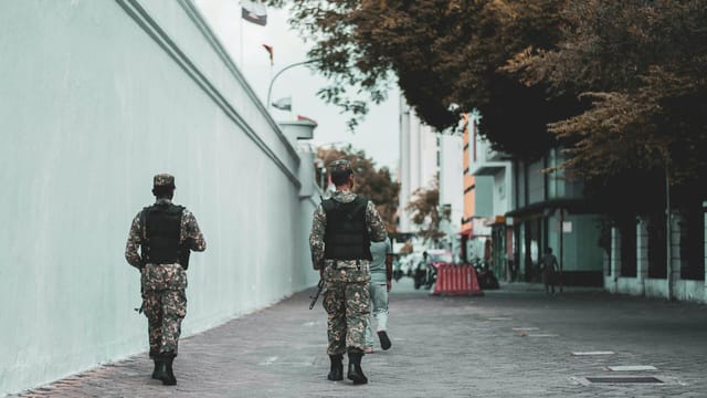 Military personnel in uniform walking along a street in Malé, Maldives.