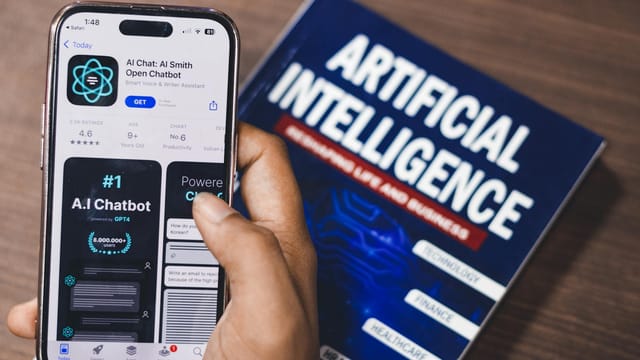 Smartphone displaying AI app with book on AI technology in background.