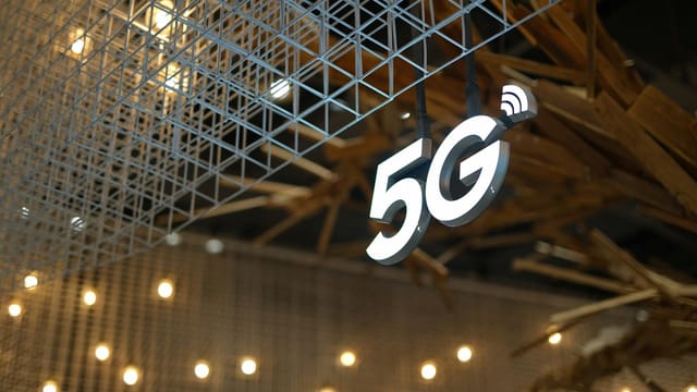 Illuminated 5G sign with modern geometric ceiling and warm lighting.